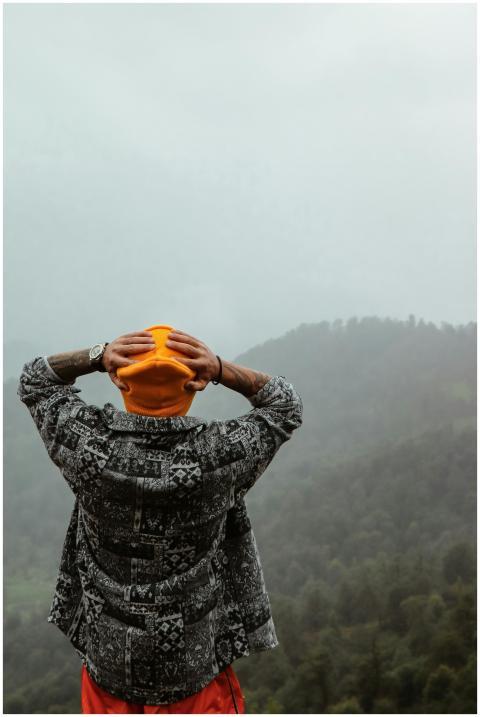 Man in patterned shirt and orange cap gazes over m