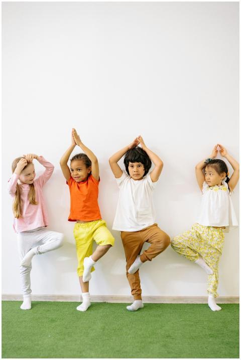Four diverse children practicing yoga indoors, pro