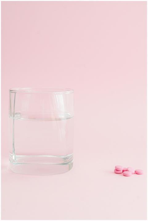 Minimalist image of a glass of water with pink pil