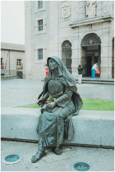A serene statue sits in a historic plaza in Ávila,