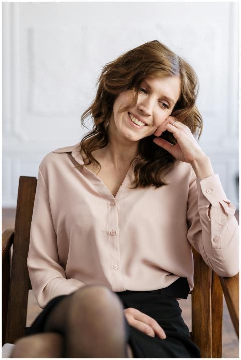 A relaxed woman with curly hair smiling while sitt