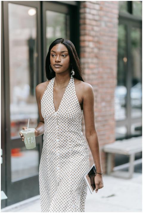 A stylish woman in a polka dot dress walks outdoor
