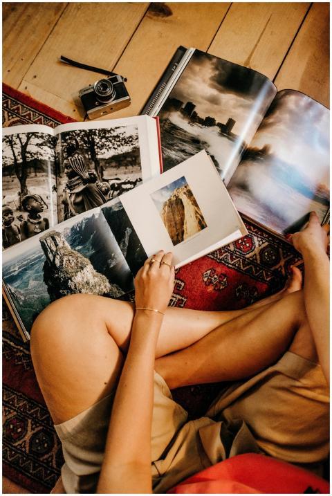 Person sitting on a rug, browsing photo books on a