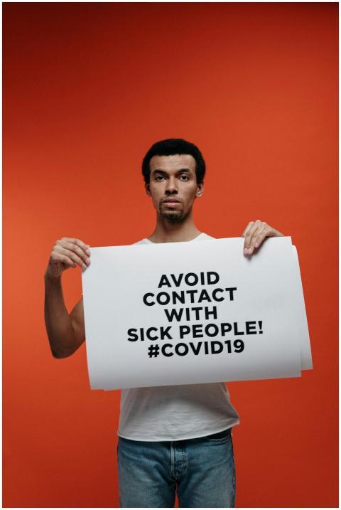 A man holds a poster warning to avoid contact duri