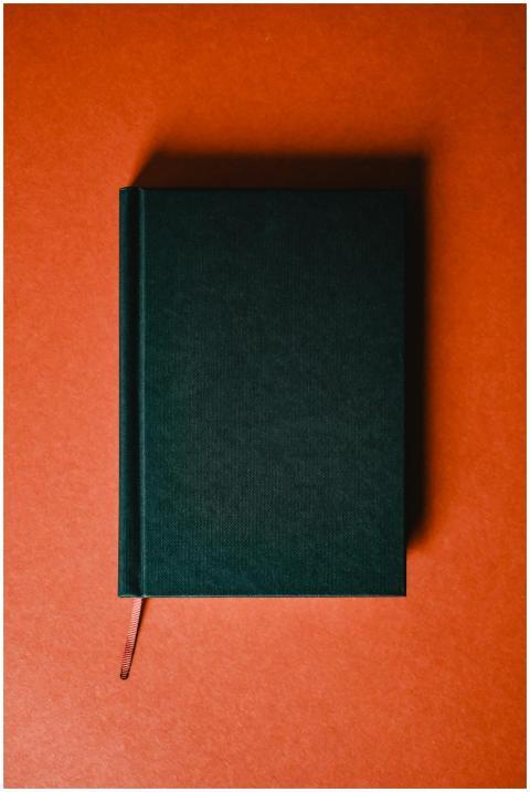 Green hardcover notebook placed on an orange backg