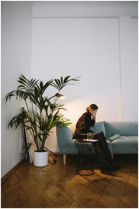A woman sits on a sofa with a laptop, surrounded b