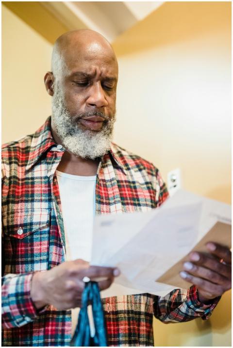 A mature man with a beard attentively reading docu