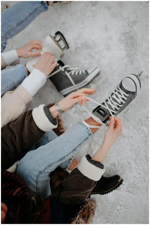 Women tying shoelaces on ice skates on a snowy win