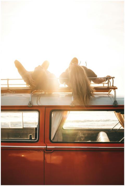 Two people enjoying a sunset on a vintage car's ro