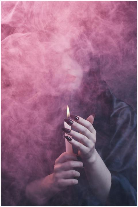 A mysterious figure holding a candle, enveloped in