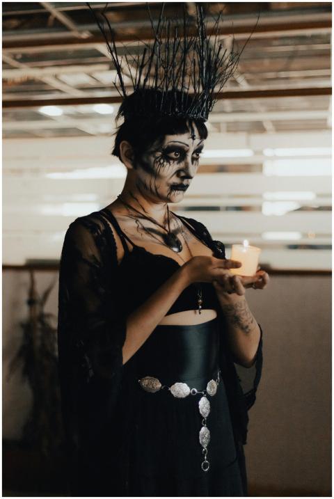 A woman in a dramatic Halloween costume holds a li