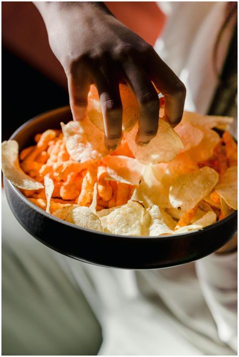 Crop anonymous female eating salty tasty crisps in