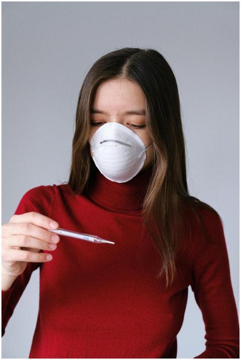 Woman in red sweater wearing mask checks temperatu