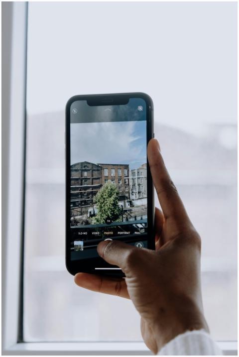 A hand holding a smartphone photographing a city b