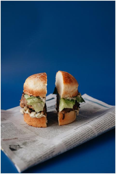 Appetizing burger halves with lettuce on a newspap