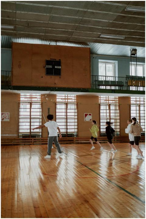 A group of children running in a gymnasium with wo