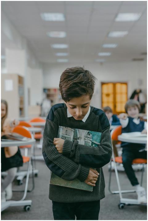 Sad boy holding books tightly, showing signs of bu