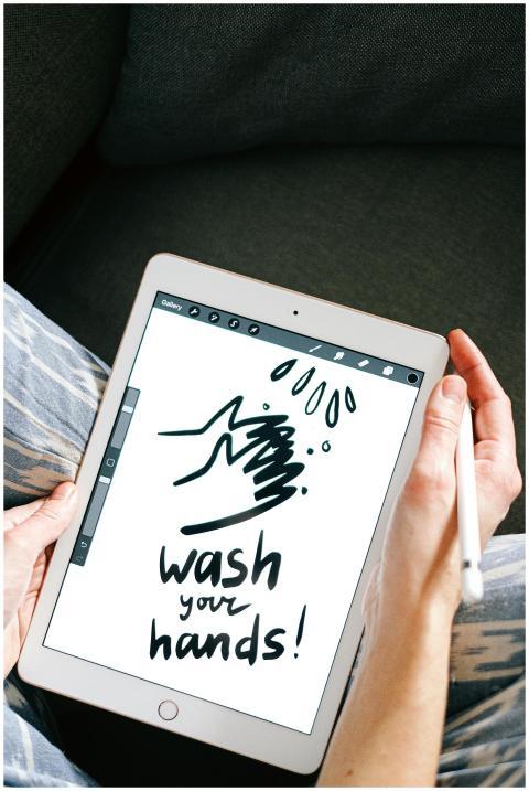 A person holding a tablet displaying a handwashing