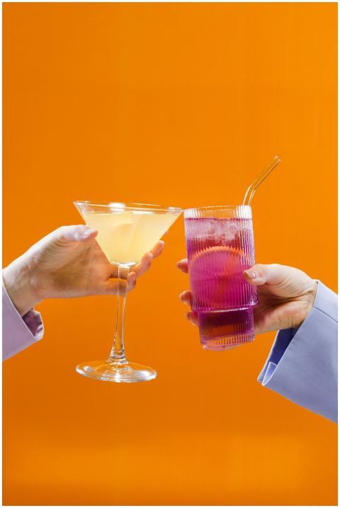 Two colorful cocktails raised for a toast against