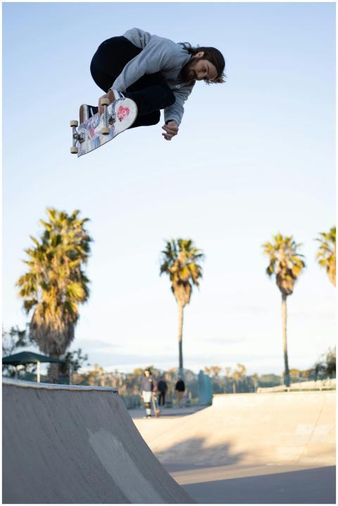 Skateboarder executing a high jump trick in a sunn