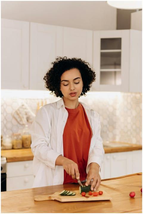 A woman with curly hair slices vegetables for a fr