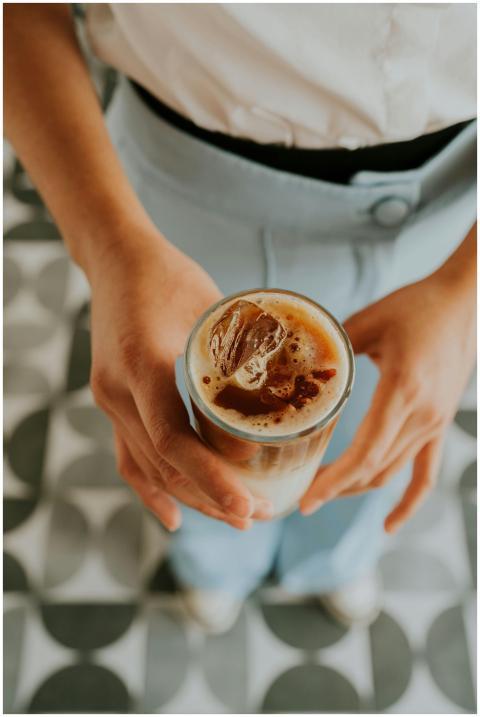 Close-up of iced coffee held by person on patterne