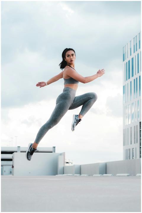 An athletic Asian woman in sportswear jumping mid-