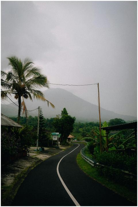 A scenic rural road in Bali, Indonesia, with foggy
