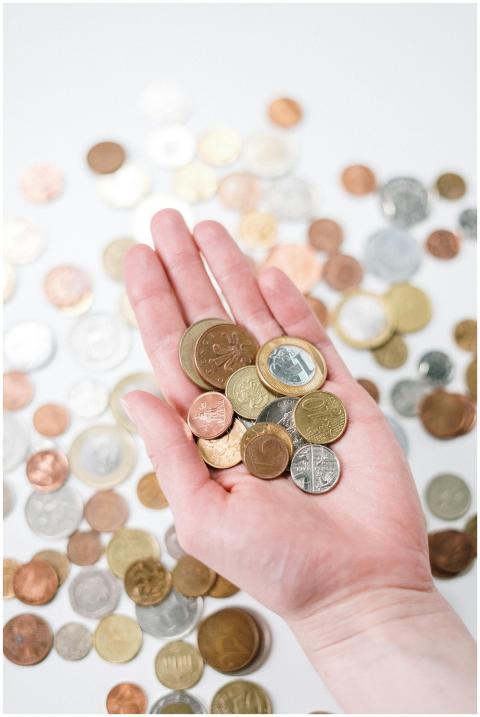 Close-up of a hand holding diverse coins, symboliz