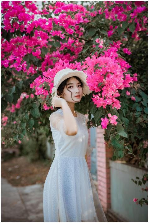 A beautiful woman wearing a white dress and hat st