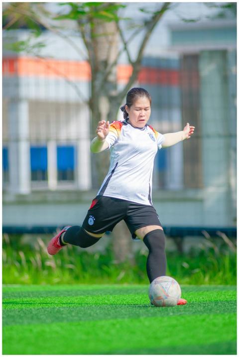 A woman kicks a soccer ball during a game on a sun