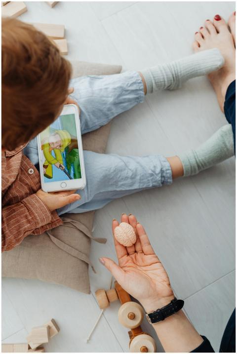A child watching a video on a smartphone while adu