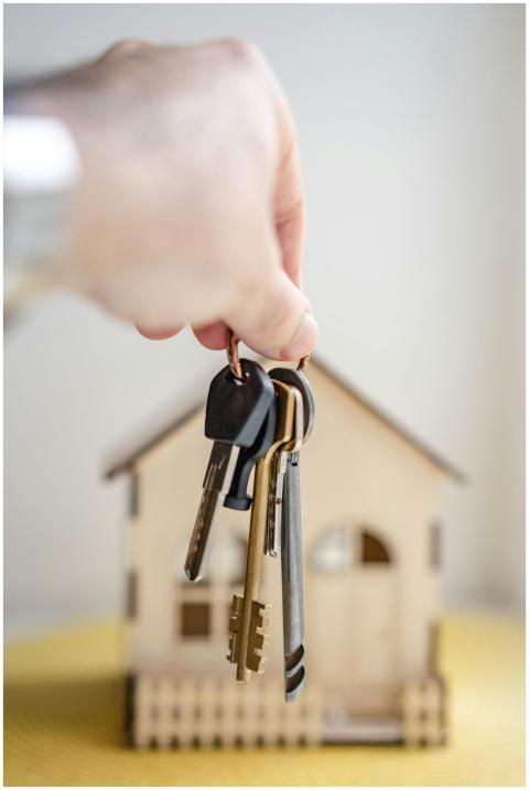 Close-up of a hand holding keys with a miniature w
