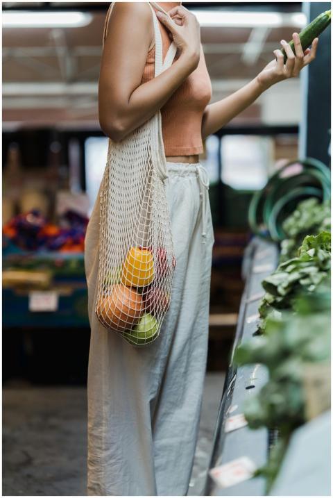 A woman shopping at a market with a mesh tote bag