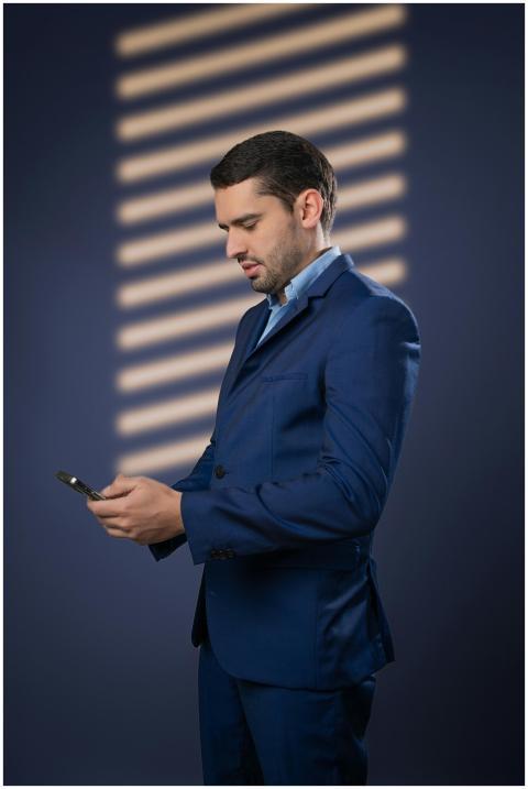 Professional man in blue suit checks his smartphon