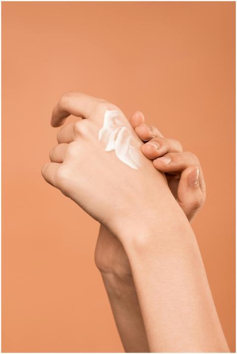 Close-up of hands applying moisturizer, promoting