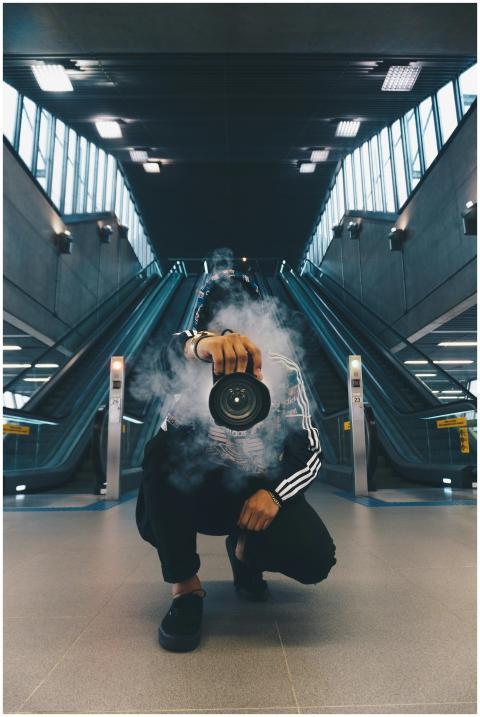Person holding a camera in a smoke-filled urban se