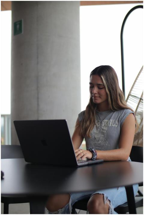 A young woman focused on her laptop, studying in a
