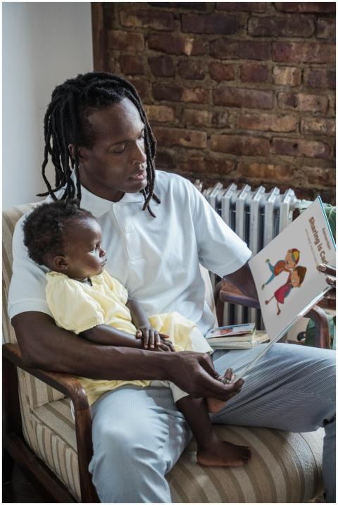 A father reads a storybook to his young child, fos