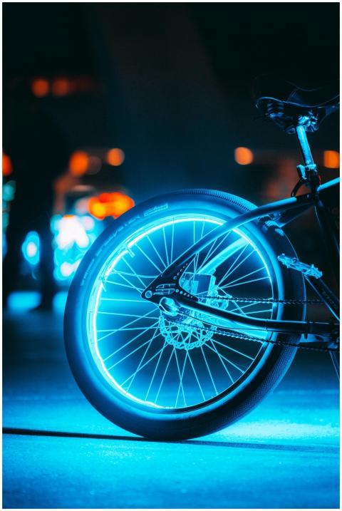 A close-up of a glowing bicycle wheel on a city st