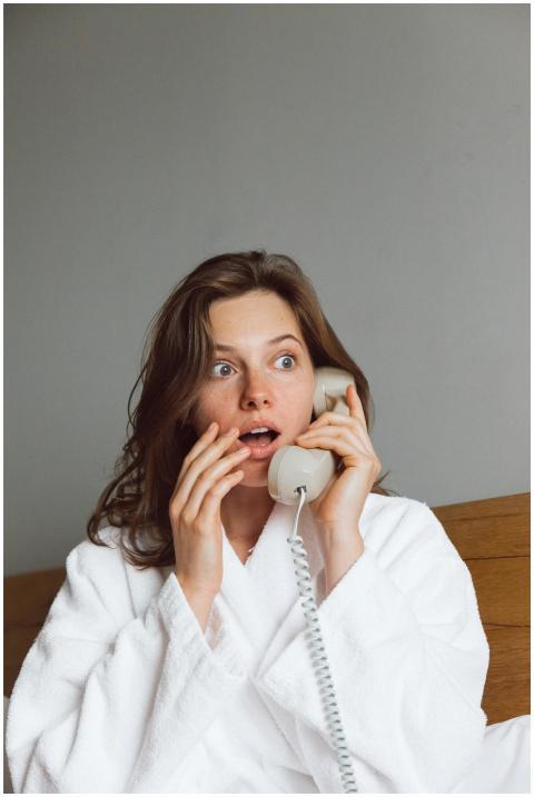 A woman in a bathrobe looks shocked while talking