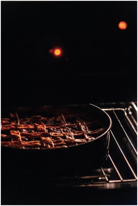 A cherry pie with a lattice crust bakes in the ove