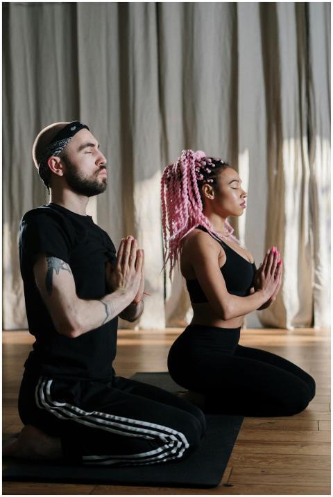 Two people practicing yoga indoors, focusing on mi