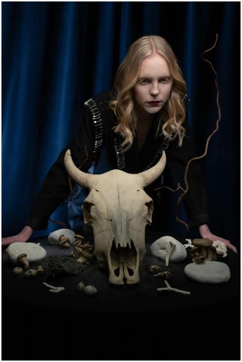 A mysterious woman poses with an animal skull and