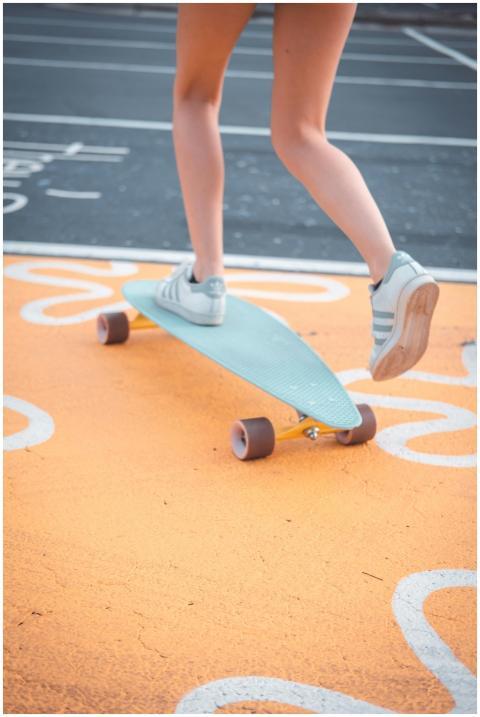 A woman rides a skateboard on a vibrant orange roa