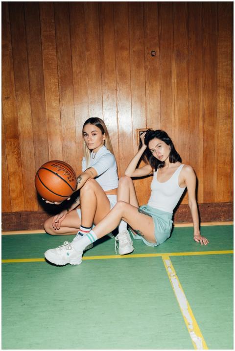 Two fashionable women posing with a basketball ind