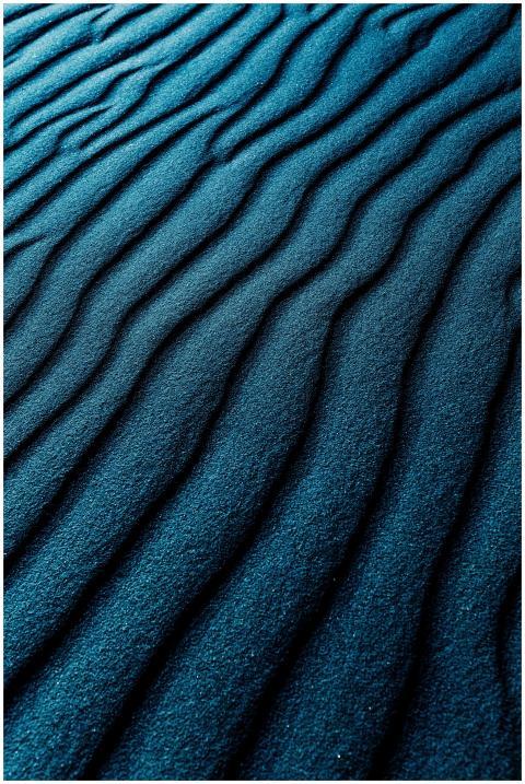 Close-up of dark blue textured sand dunes with a w