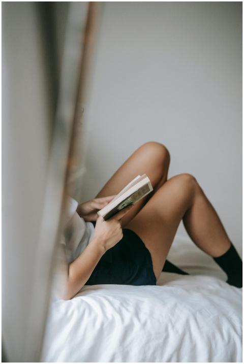 Woman lying on bed, reading a book in a peaceful,