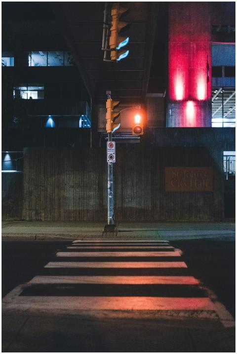 A nighttime urban street scene featuring a crosswa
