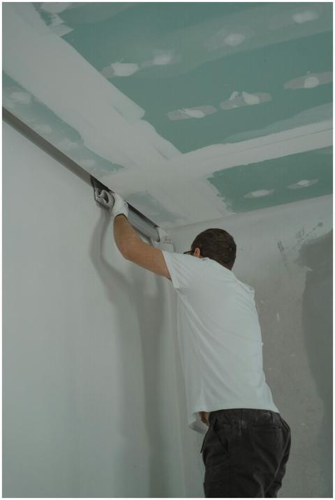 A man works meticulously on drywall installation d